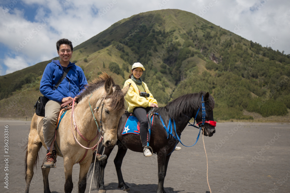 Traveler couple ride a horse at Mt. Bromo, east Java, Indonesia.