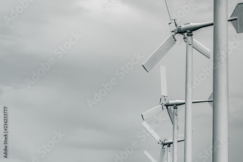 Horizontal axis wind turbine with grey sky and clouds. Wind energy in eco wind farm. Green energy concept. Renewal energy. Alternative electricity source. Sustainable resources. photo