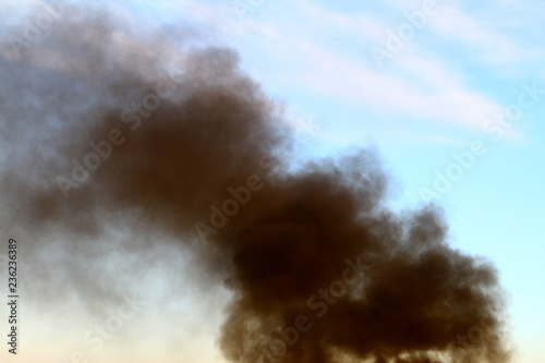 black smoke pillar against blue sky background.