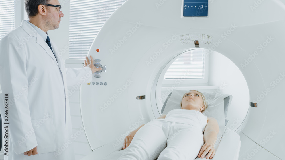 In Medical Laboratory Radiologist Controls MRI or CT or PET Scan with Female Patient Undergoing Procedure. High-Tech Modern Medical Equipment. In Medical Laboratory Radiologist Controls MRI or CT or PET Scan with Female Patient Undergoing Procedure. High-Tech Modern Medical Equipment.