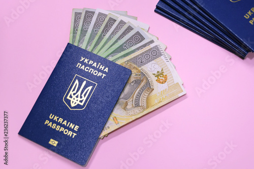 Ukraine passports with golden letters and trident emblem on violet blurred background. Stack of id documents with poland currency polish zloty. Ukrainiant migrant wokers documents. photo