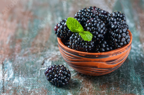 Blackberries in a ceramic bowl on wooden background close up. Rustic style photo