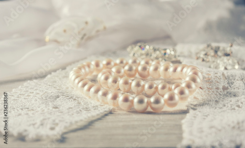 White pearl necklace on handmade lace background. Photo toned