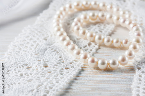 White pearl necklace on handmade lace background.