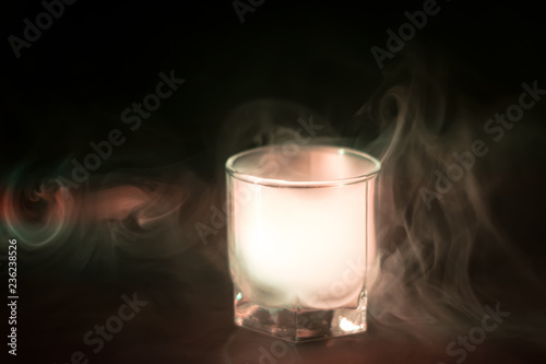 white, green smoke (evaporation) in a glass bowl on a black background