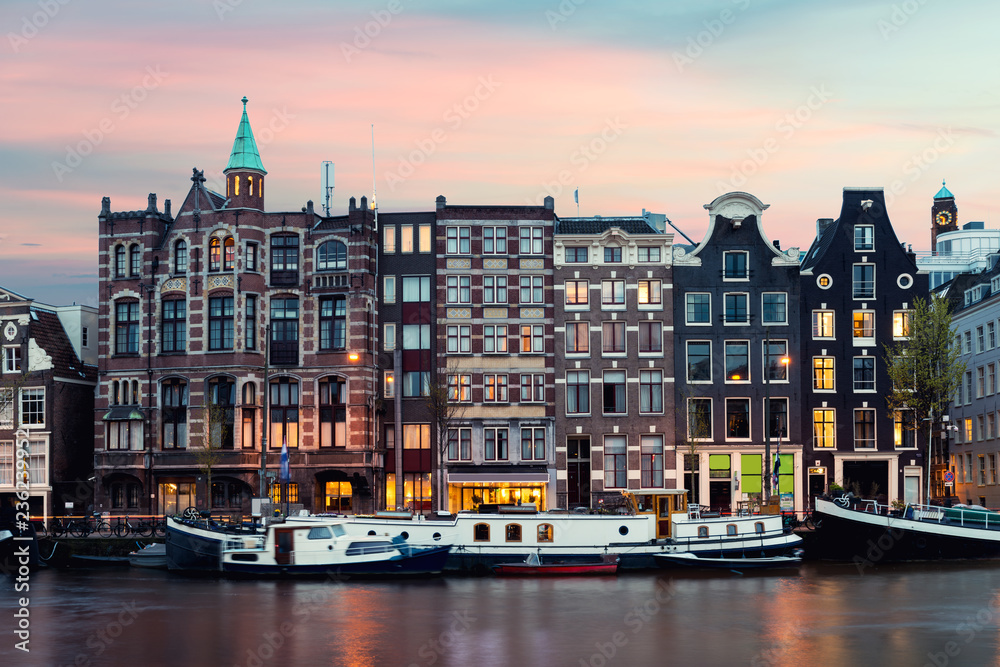 Naklejka premium Night Amsterdam city view of Netherlands traditional houses with Amstel river in Amsterdam, Netherlands