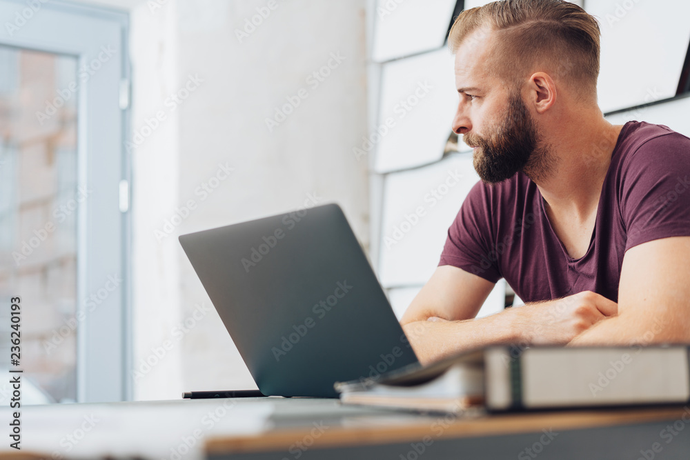 Modern, metro man working on laptop in home office Modern, metro man working on laptop in home office