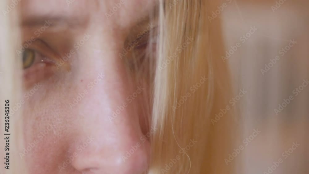 A blond woman with long hair is combing in front of a mirror, preparing her head for coloring hair roots. A blond woman with long hair is combing in front of a mirror, preparing her head for coloring hair roots.