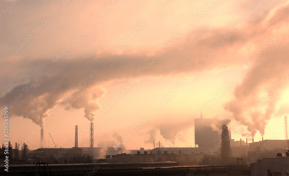 Industrial plant pollutes atmosphere and environment with harmful emissions from chemical processing through factory chimneys against cloudy sky