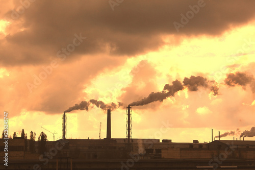 Industrial plant pollutes atmosphere and environment with harmful emissions from chemical processing through factory chimneys against cloudy sky