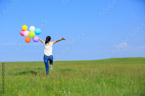 Young asian woman running and jumping with colored balloons