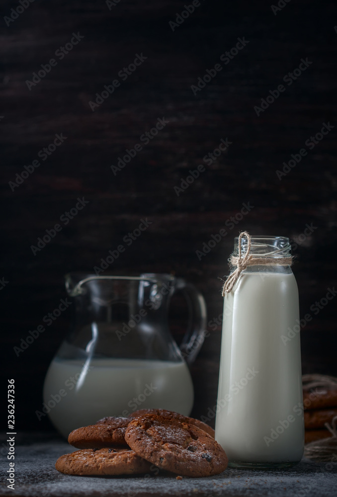 Oatmeal cookies with raisins, chocolate and milk in bottles, wood background Oatmeal cookies with raisins, chocolate and milk in bottles, wood background