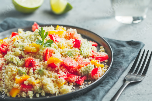 Couscous salad with fresh red and yellow bell peppers, avocado, tomatoes and lime. The concept of vegetarian and healthy food.
