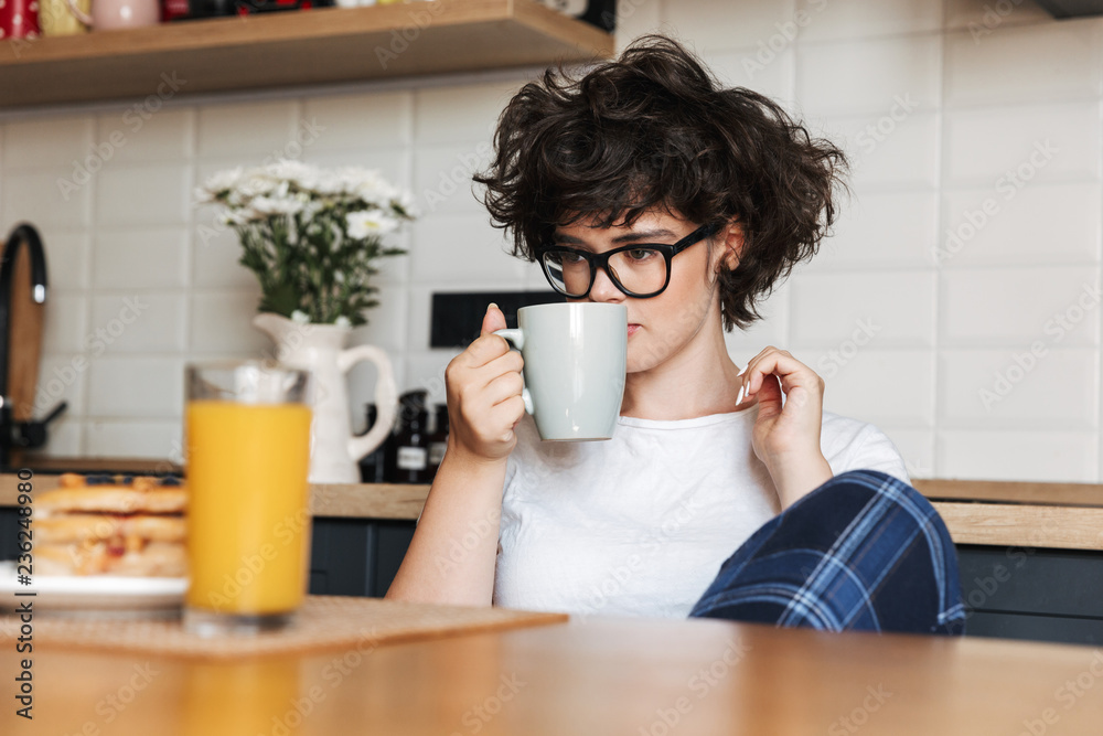 Curly woman sitting at the kitchen drinking tea. Curly woman sitting at the kitchen drinking tea.