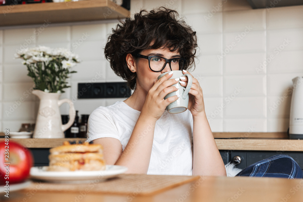 Curly woman sitting at the kitchen drinking tea. Curly woman sitting at the kitchen drinking tea.