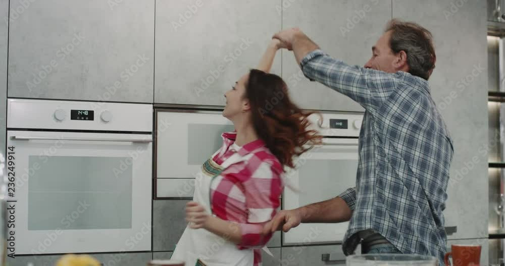 Morning in the kitchen romantic mature couple dacing while making the breakfast in the morning.