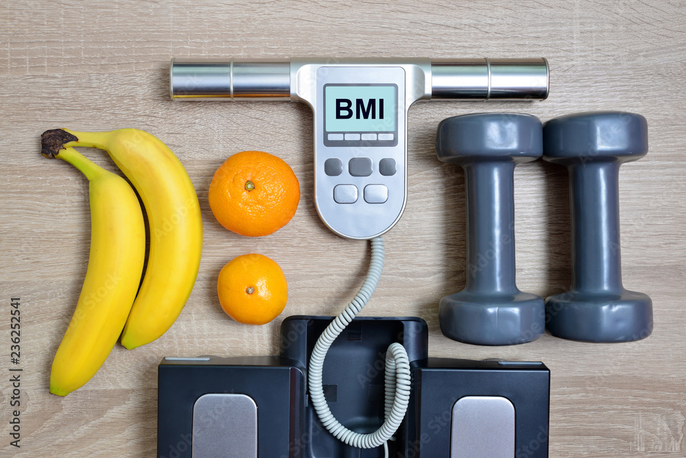 Body Mass Index Scale with fruits and dumbbells on wooden board.Healthy lifestyle concept. Body Mass Index Scale with fruits and dumbbells on wooden board.Healthy lifestyle concept.