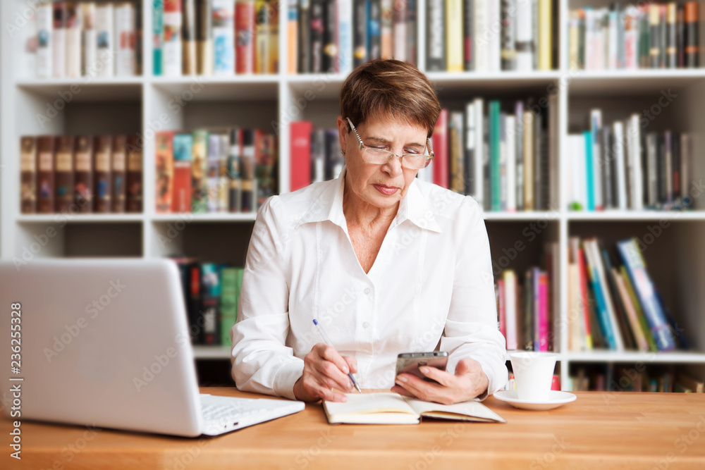 Senior woman is using a smartphone sitting at a table
Senior woman is using a smartphone sitting at a table