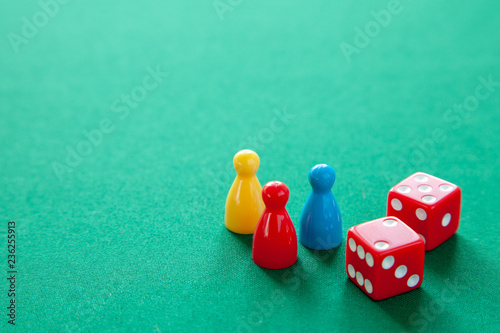 Colored game figures chips for board games. Collection of dice cubes on green table. Copy space for text photo