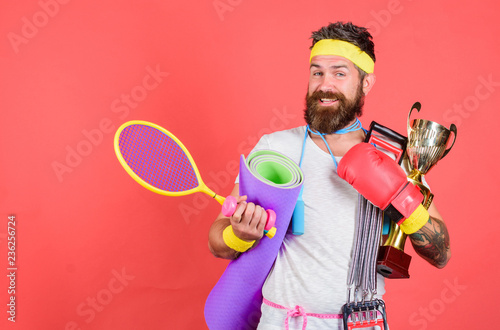 Man bearded athlete hold sport equipment jump rope fitness mat boxing glove expander racket and golden goblet. Choose sport you like. Sport lifestyle concept. My goal is health. Sport shop assortment © be free