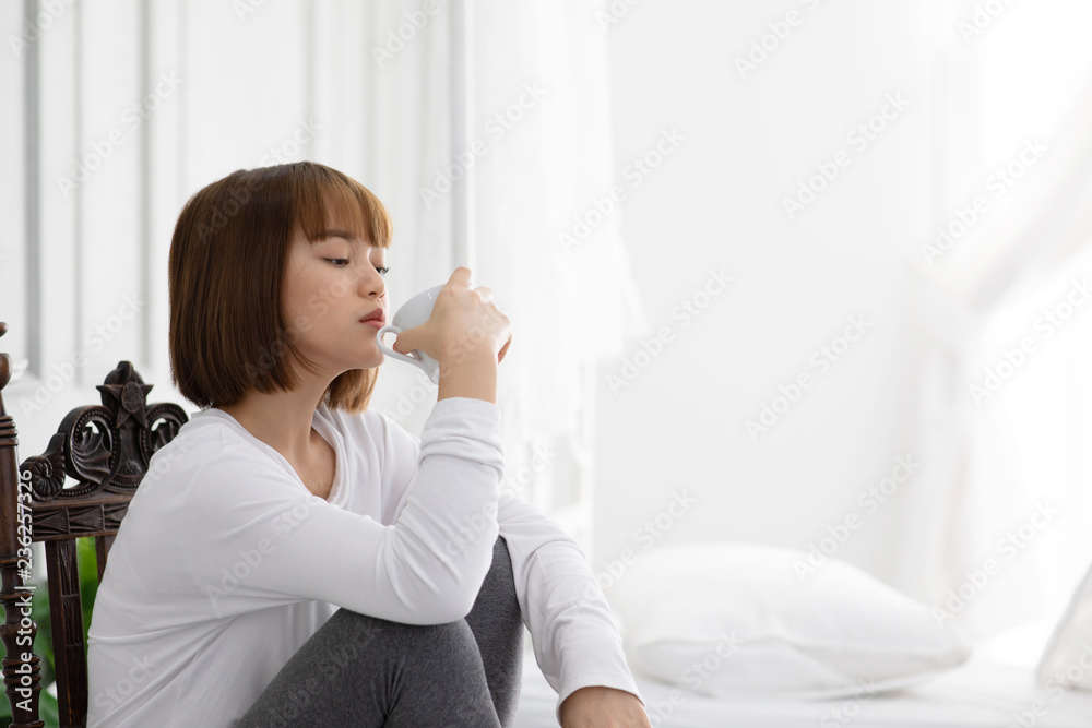 Beautiful Attractive Asian young woman sitting on wooden chair and relax with coffee after wake up in the morning in bedroom feeling so comfortable and happiness Beautiful Attractive Asian young woman sitting on wooden chair and relax with coffee after wake up in the morning in bedroom feeling so comfortable and happiness