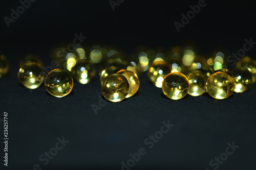 Fish oil in bright capsules on a black background.