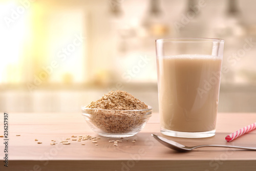 Oat drink in glass and cereal flakes on kitchen bench