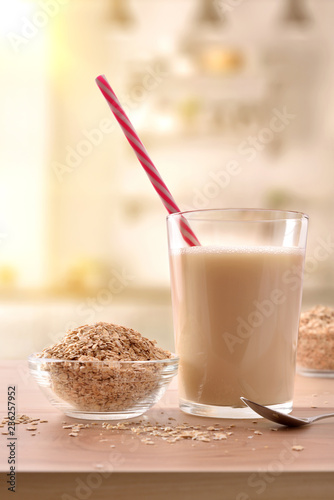 Oat drink in glass and cereal flakes on kitchen vertical