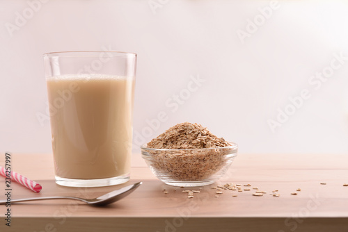 Oat drink in glass and cereal flakes white background