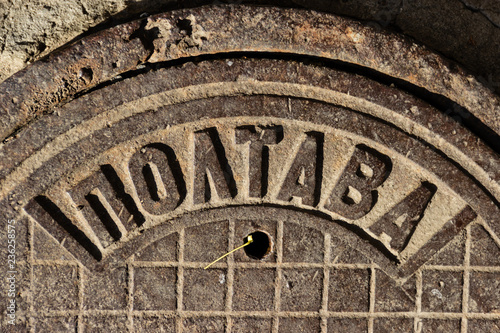 Vintage cast-iron sewer manhole USSR made with the inscription POLTAVA in the city of Dnipro, Ukraine, November 2018 (fragment). Theft of manhole covers has become a frequent occurrence since 2014. photo