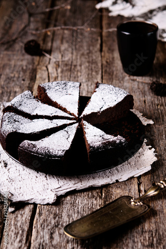 Kladdkaka. Traditional Swedish moist chocolate cake on old rustic wooden table decorated dry twigs, pine cones and birch bark. Fika. Hygge