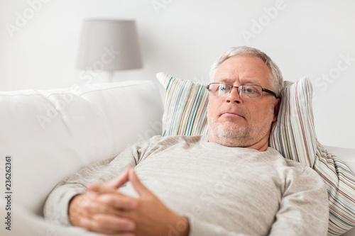 old age, problem and people concept - senior man  lying on sofa and thinking at home © Syda Productions