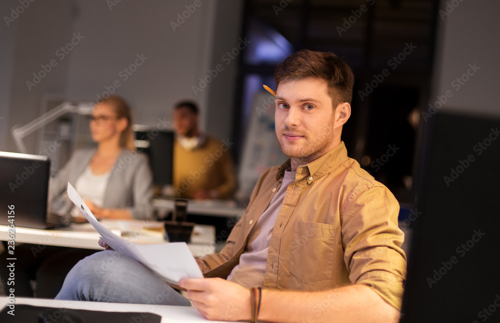 business, deadline and people concept - man with papers working at night office business, deadline and people concept - man with papers working at night office