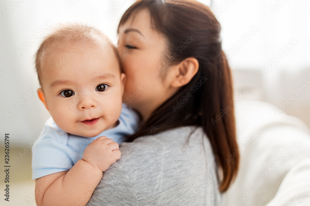 family and motherhood concept - close up of happy young asian mother kissing little baby son at home family and motherhood concept - close up of happy young asian mother kissing little baby son at home