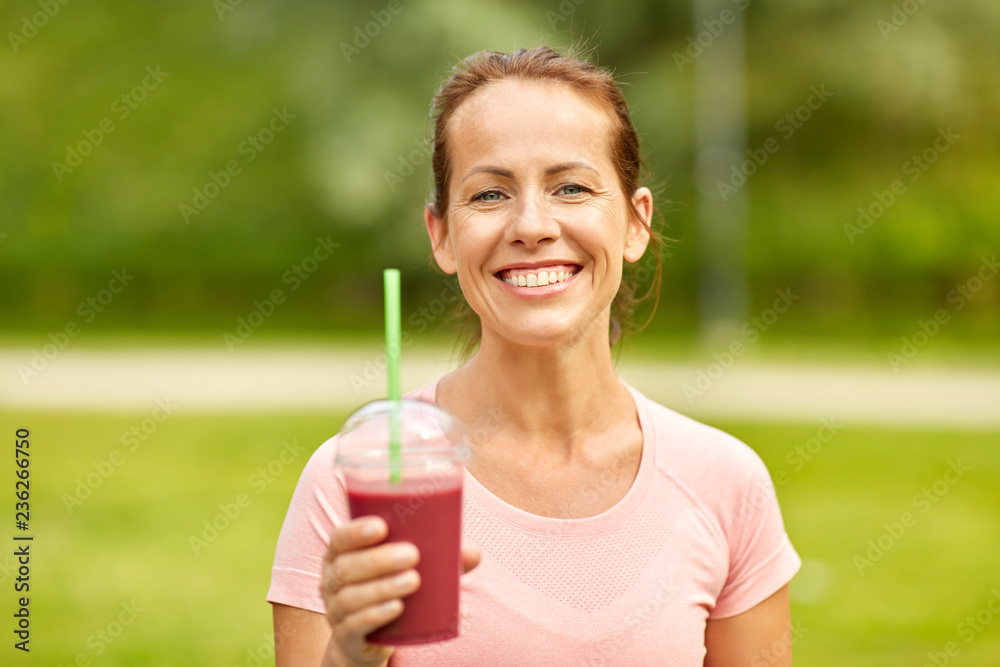 fitness, sport and healthy lifestyle concept - woman drinking takeaway smoothie or shake from plastic cup after exercising at summer park fitness, sport and healthy lifestyle concept - woman drinking takeaway smoothie or shake from plastic cup after exercising at summer park