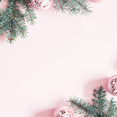 Christmas composition. Frame made of fir tree branches, pink balls on pastel pink background. Christmas, winter, new year concept. Flat lay, top view, copy space, square