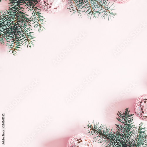 Christmas composition. Frame made of fir tree branches, pink balls on pastel pink background. Christmas, winter, new year concept. Flat lay, top view, copy space, square