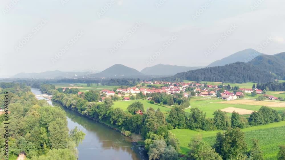 We can see a small village in the middle of the cuntryside and a wide river nearby. It's summer time. Aerial shot. We can see a small village in the middle of the cuntryside and a wide river nearby. It's summer time. Aerial shot.