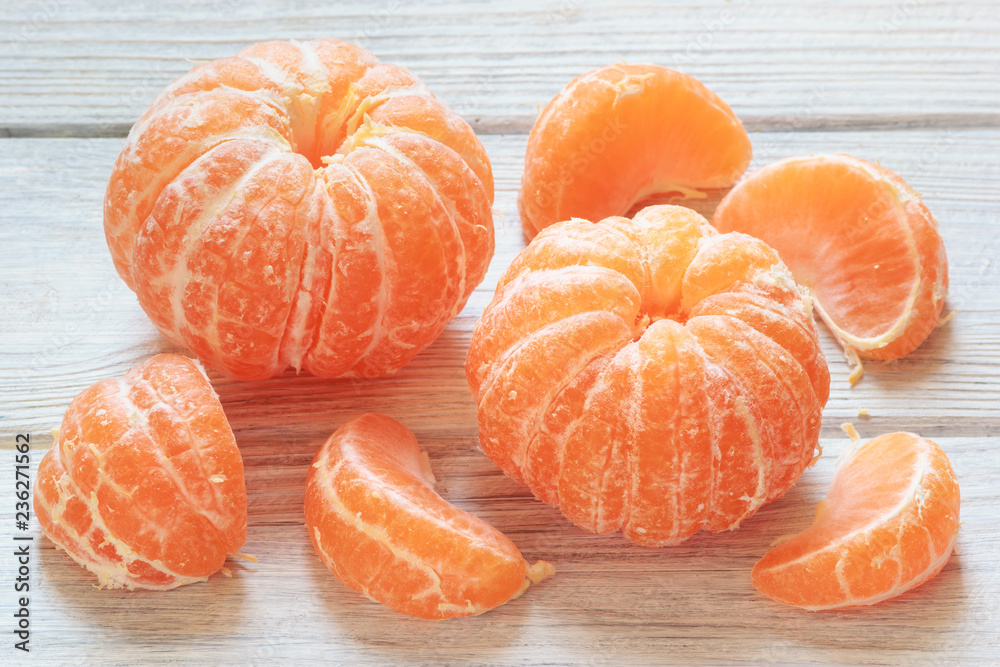 Tangerine mandarines peeled on white wooden table background