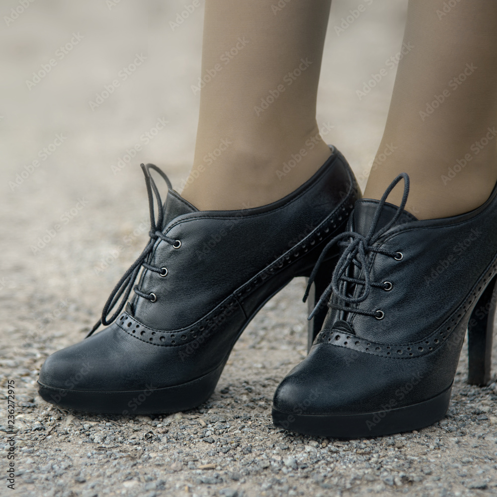 Fashion concept of women's feet in black shoes with high heels.