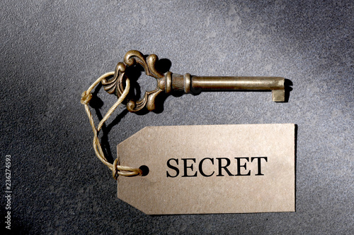 old antique key and a label with the word secret and copy space for your text rest on a slate  background