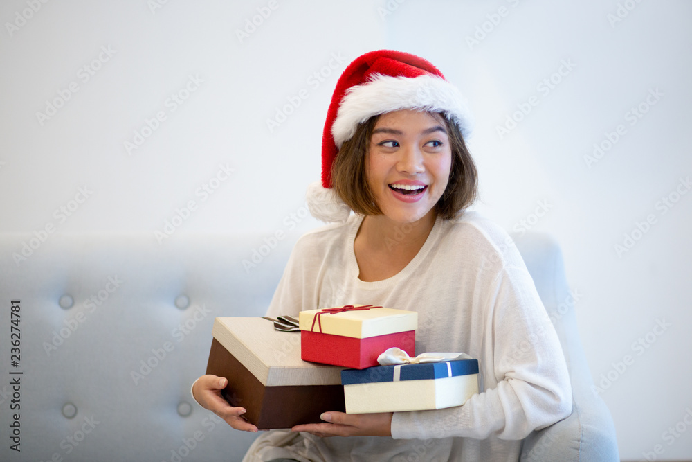 Happy Christmas girl overjoyed with gifts. Young Asian woman in Santa cap holding present boxes and smiling at camera. Christmas presents concept Happy Christmas girl overjoyed with gifts. Young Asian woman in Santa cap holding present boxes and smiling at camera. Christmas presents concept