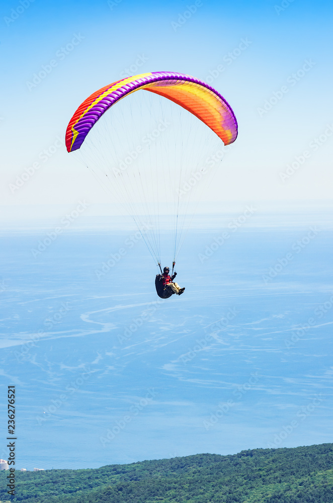 Paraglider over the sea coast. Russia, Republic of Crimea. 06.13.2018. Flight of a paraglider athlete over the sea coast in the area of Mount Ai-Petri Paraglider over the sea coast. Russia, Republic of Crimea. 06.13.2018. Flight of a paraglider athlete over the sea coast in the area of Mount Ai-Petri