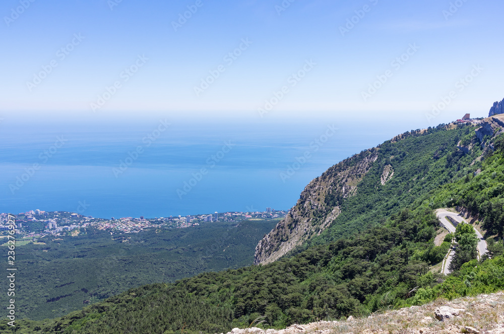 Mountain slope with a road near the sea coast. Russia, Republic of Crimea. 06.13.2018. The slope of Mount Ai-Petri with a highway and views of the Black Sea