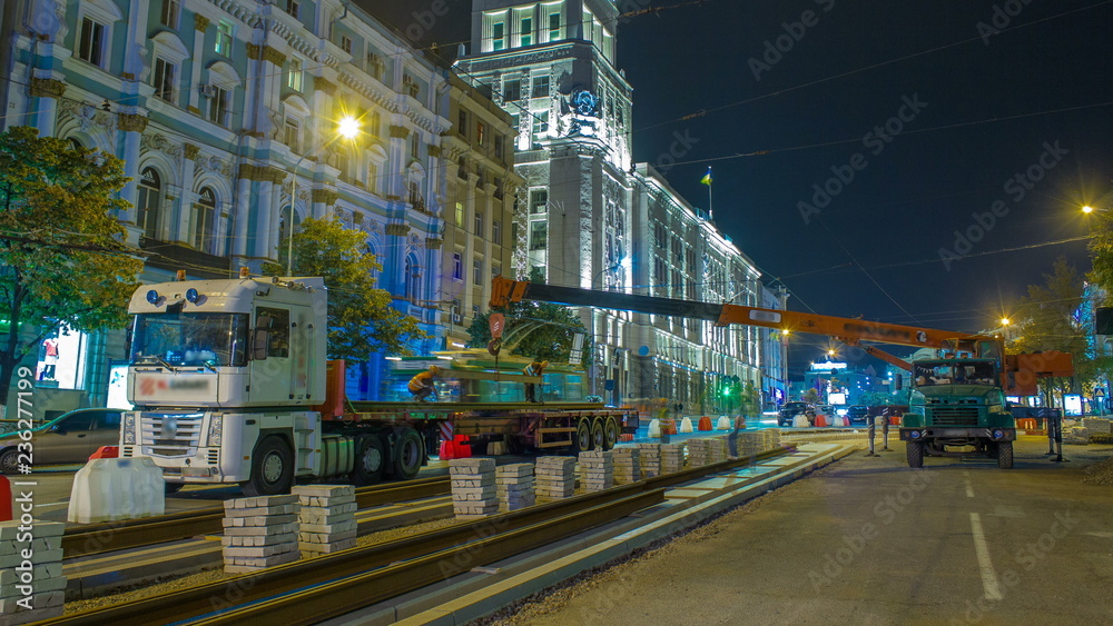 Obraz premium Orange construction telescopic mobile crane unloading tram rails from truck timelapse.