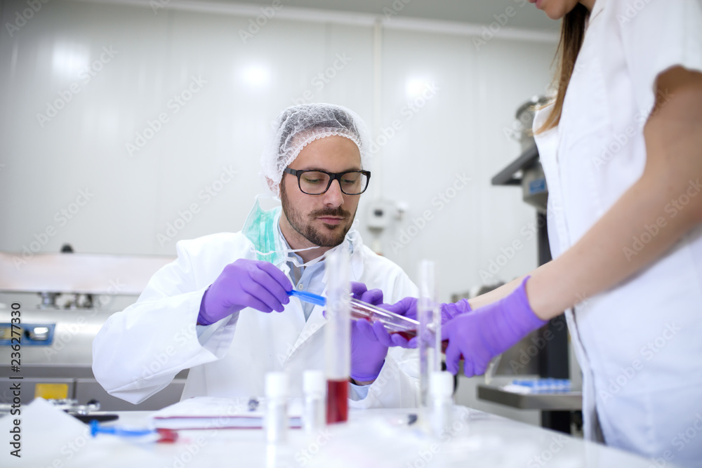 Scientist doing research in his lab while his assistant helping him. Scientist doing research in his lab while his assistant helping him.