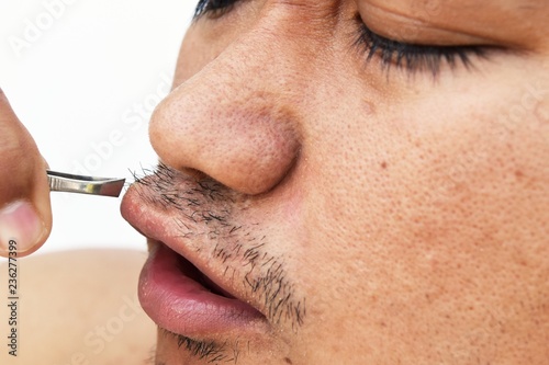 man pull mustache by tweezers on white background