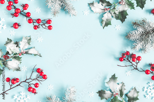 Christmas or winter composition. Frame made of snowflakes, fir tree branches and red berries on pastel blue background. Christmas, winter, new year concept. Flat lay, top view, copy space