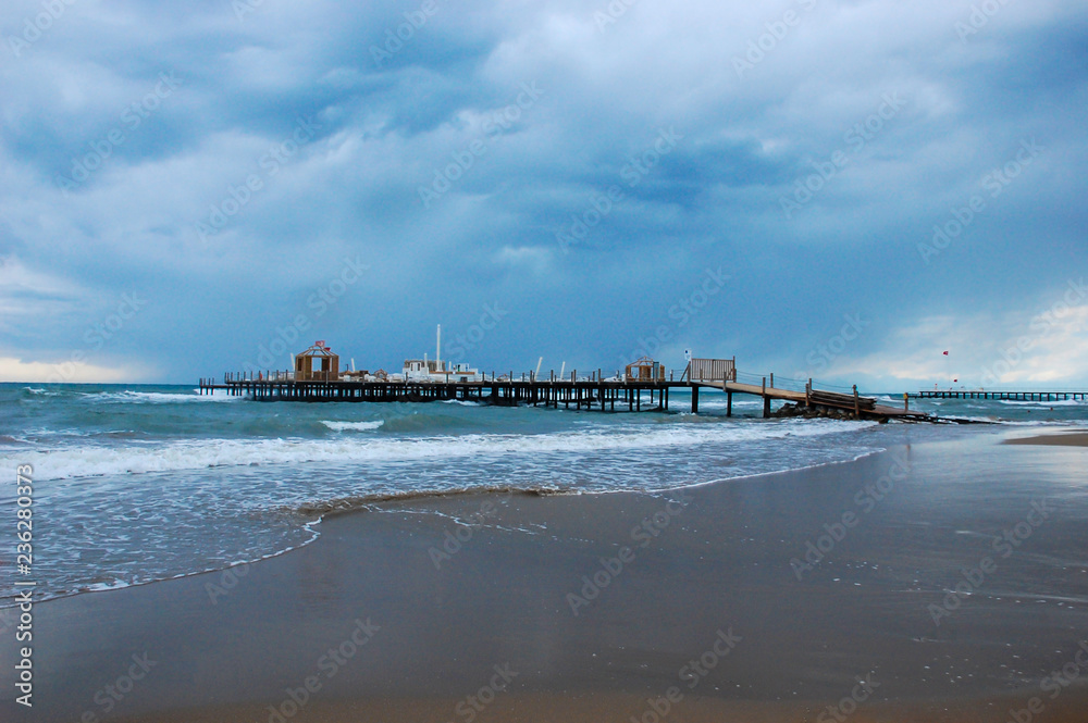 Photo of a pier on the beach in inclement weather