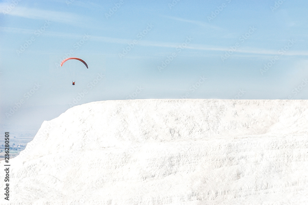 Parachutist flies on the background of the snow-white travertine mountains.